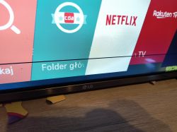 Ekran telewizora LG z czarną poziomą kreską i aplikacjami na ekranie.