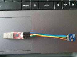 USB to TTL adapter with wires connected to a module on a laptop keyboard.