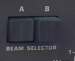 Zbliżenie dwóch przycisków podpisanych A i B na panelu oznaczonym jako BEAM SELECTOR