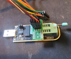 Programator CH341A z podłączonym klipsem SOP16 i przewodami na czarnym tle