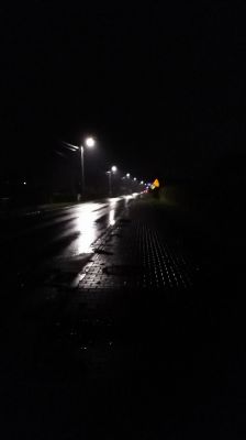 Nocna ulica oświetlona latarniami LED, z mokrym chodnikiem i nawierzchnią