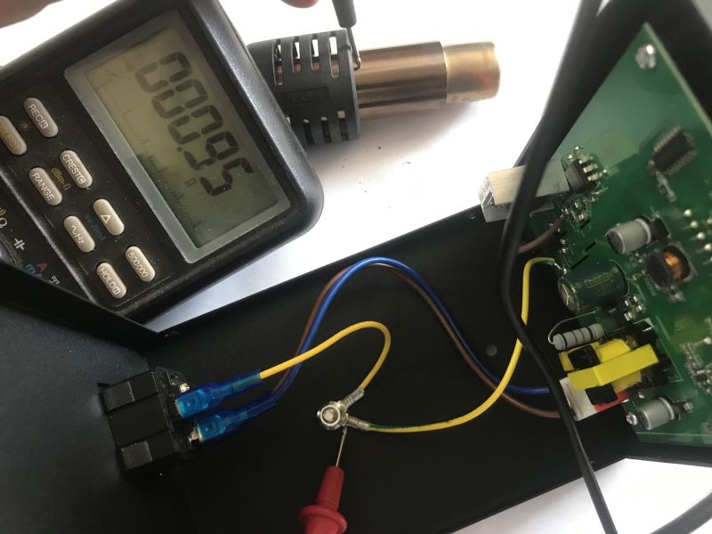 Multimeter reading 200.9 next to an opened device showing a green PCB and wiring