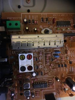 Wnętrze urządzenia elektronicznego z widocznymi układami scalonymi, elementami lutowanymi oraz kondensatorami na płytce drukowanej.