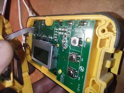 Wnętrze żółtego urządzenia z płytką PCB, wyświetlaczem i trzema przyciskami