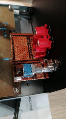Układ elektroniczny na płytce drukowanej z czerwonymi złączami i niebieskim elementem.