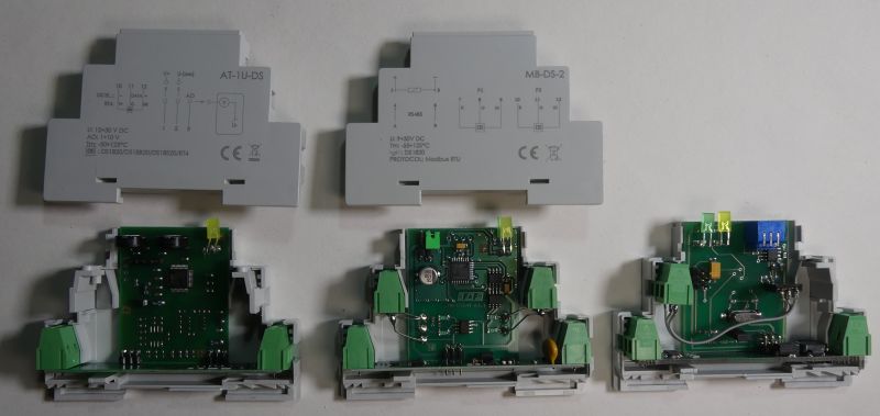 Otwarte obudowy modułów elektronicznych do montażu na szynie DIN z widocznymi płytkami PCB i złączami.