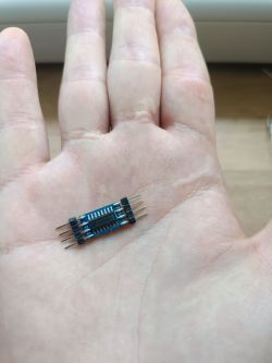 Mały moduł elektroniczny na dłoni z pinami po obu stronach.