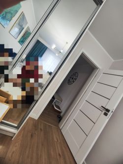 Szafa z lustrem w pokoju z drewnianą podłogą i białymi ścianami.