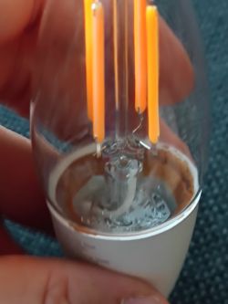 Close-up of an LED bulb showing filaments and a white wire inside.