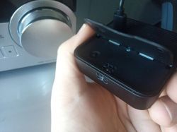 Person holding a black device with an open flap next to a silver electronic device.