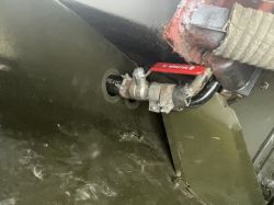 Zawór kulowy z czerwoną dźwignią na przewodzie opisanym „HEATER” w zielonym wnętrzu pojazdu