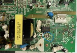 Nahaufnahme einer beschädigten Leiterplatte mit verbrannten Bauteilen neben dem FSL136MR-IC, markiert mit einem blauen Kreis.