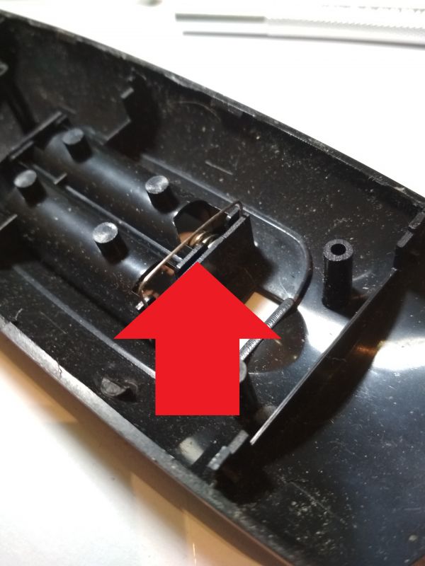 Wnętrze obudowy pilota z oznaczeniem miejsca na styki baterii.