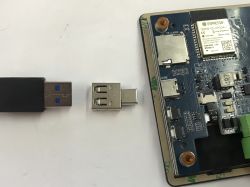 ESP32-S3 board with USB-C port next to a USB-A to USB-C adapter and a USB-A plug