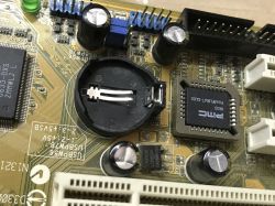 Close-up of a computer motherboard with a battery socket and components.