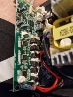 Close-up of a speaker’s main circuit board with visible capacitors and connected wires.