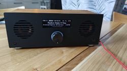 Black radio with wooden top on a table, display reading “Radio Italo 4 You” and a front knob