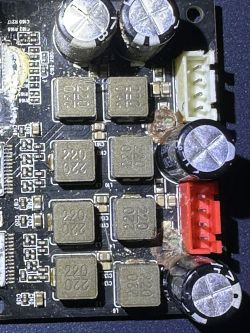 Zbliżenie na płytkę PCB ze spuchniętymi kondensatorami i uszkodzeniami ścieżek.