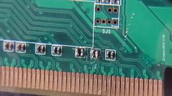 Zbliżenie płytki PCB z padami i stykami złącza oraz miejscem lutowania obok napisu „SJ1”