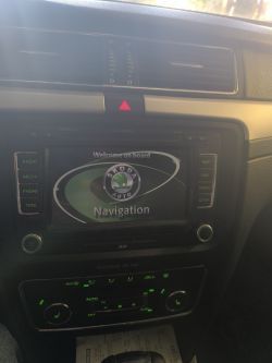 Ekran systemu nawigacji w samochodzie marki Škoda z widocznym logo i opcjami sterowania radiem oraz klimatyzacją.