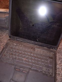 Brudny laptop IBM ThinkPad z otwartą klapą i porysowanym, ciemnym ekranem