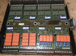 Inside a modular controller: four green PCBs with orange relay blocks, many ICs, and screw terminal strips