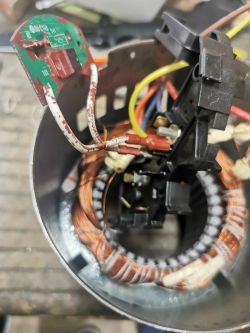 Zbliżenie na wewnętrzny mechanizm silnika jednofazowego z widocznymi uzwojeniami miedzianymi oraz zamocowaną płytką drukowaną.