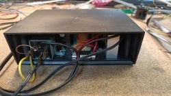 Otwarta czarna obudowa z elektroniką i przewodami na blacie warsztatowym