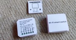 Wi-Fi Smart Switch with Packaging Wi-Fi Smart Switch and its packaging on a carpet.