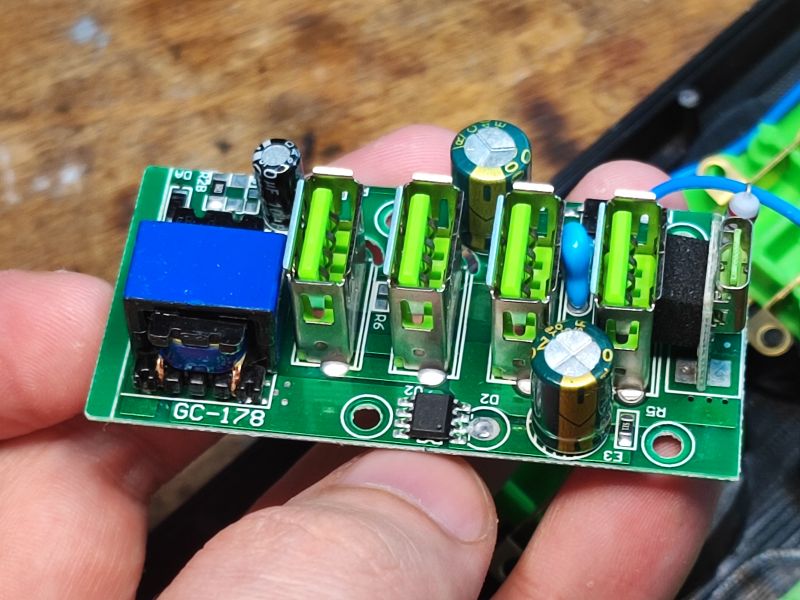 Płytka drukowana z pięcioma portami USB i elementami elektronicznymi, trzymana w dłoni.