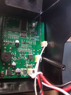 Zdjęcie płytki drukowanej z kilkoma podłączonymi przewodami wewnątrz urządzenia elektronicznego.