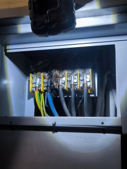 Spalona instalacja elektryczna w skrzynce z widocznym uszkodzeniem przewodów.