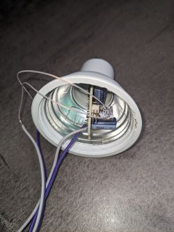 Dismantled LED bulb with visible wires and circuit board.