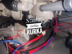 Wnętrze zmywarki z rurkami i przewodami, widoczna szara rurka opisana jako szara, cienka rurka.