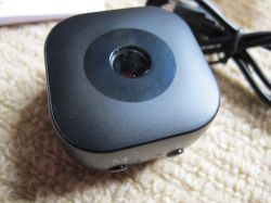Webcam with USB Cable A black, square-shaped webcam with a central lens and attached USB cable, lying on a carpet.