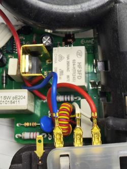 Zbliżenie na płytkę drukowaną z elementami elektronicznymi, przekaźnikiem HF3FD, złączami i przewodami.