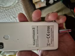 Tył telefonu SmartVision 3 trzymanego w ręce z widoczną naklejką producenta.