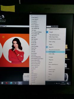 Ekran laptopa z listą kanałów telewizyjnych i radiowych oraz kobietą w czerwonym swetrze.