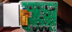 Close-up of a green circuit board with several electronic components and a connected ribbon cable.