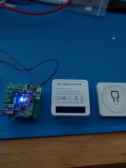 Printed circuit board and casing of a mini smart switch on a blue workspace mat.