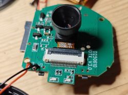 Camera module on PCB with lens and ribbon connector Camera module with lens mounted on a green printed circuit board