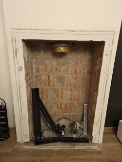 Dismantled Fireplace with Ventilation Elements Interior of a dismantled fireplace with visible ventilation elements and wires.