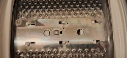 Wnętrze bębna pralki z metalową płytą i otworami montażowymi pod zabierak