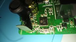 Close-up of green PCB with microcontroller, capacitors, and surface-mount components.