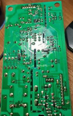 Zbliżenie na uszkodzoną zieloną płytkę PCB z przypaloną ścieżką i lutami.