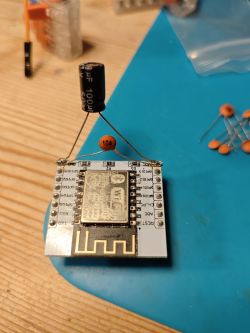 Electronic module with a soldered capacitor on a wooden surface.