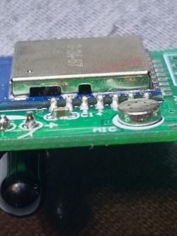 Close-up of an electronic module with metal casing and soldered pins on a circuit board.