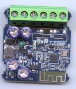 Close-up of a blue PCB module with a green screw terminal block and capacitors