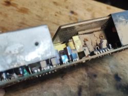 Zbliżenie na wnętrze zasilacza elektronicznego z widocznymi śladami korozji oraz brudu.