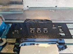 Czarny aluminiowy panel frontowy subwoofera z oznaczeniami.